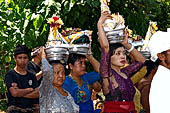 Cremation ceremony - The villagers line up, each with something to carry: holy water, ritual accessories, pyramids of food offerings piled high on their heads.