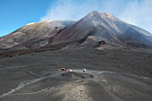 Etna - From Piccolo Rifugio to the Torre del Filosofo. The Baita delle Guide parking lot of the jeeps at the Rifugio Torre del Filosofo below the towering crater of North East.
