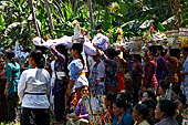 Cremation ceremony - The villagers line up, each with something to carry: holy water, ritual accessories, pyramids of food offerings piled high on their heads. 