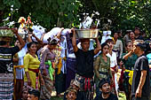 Cremation ceremony - The villagers line up, each with something to carry: holy water, ritual accessories, pyramids of food offerings piled high on their heads. 
