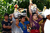 Cremation ceremony - The villagers line up, each with something to carry: holy water, ritual accessories, pyramids of food offerings piled high on their heads. 