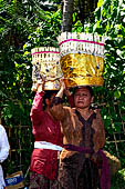 Cremation ceremony - The villagers line up, each with something to carry: holy water, ritual accessories, pyramids of food offerings piled high on their heads. 