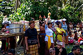 Cremation ceremony - The villagers line up, each with something to carry: holy water, ritual accessories, pyramids of food offerings piled high on their heads. 