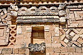 Uxmal - The Nunnery Quadrangle, the North Building. The frieze over the fifth doorway: a hut with two headed serpents above it and two jaguars with intertwined tails below. 