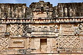 Uxmal - The Nunnery Quadrangle, the North Building. Frieze between the first and the second masks stack with a traditional hut surmounted by three double-headed serpents.  