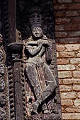 Changu Narayan - Detail of carved wooden figures (Krishna playing the flute) on the pilgrim rest houses surrounding the temple courtyard. 