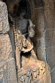 Hirapur - the Sixtyfour Yoginis Temple, male image on the right side wall of the vestibule. Note the garland of skulls anf d the anklets of snakes, he holds a skull cup. On the pedestal there is a plant among figures of attendands. 