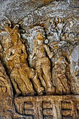 Udaigiri Cave 1 Rani Gumpha Queen's Cave - decorations of the three doorways of the veranda of the left wing of the ground floor. The last scene contains three figures one is the raja with a plumed head dress followed by his wife and a child.