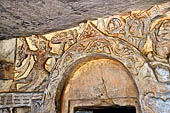 Udaigiri Cave 1 Rani Gumpha Queen's Cave - friezes of the upper storey. The story of a Kalinga queen carried away by Ashoka. First tableau: a man running with a tray in one hand. The large swastika is part of the following tableau. 